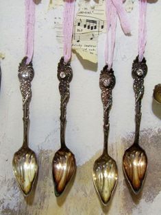 four spoons hanging from the side of a wall with music notes attached to them