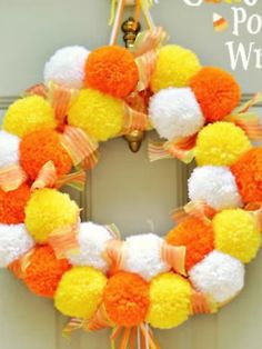 an orange and white pom - pom wreath hanging on a door