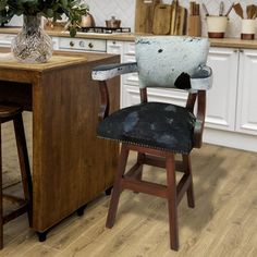 an old chair sits in the middle of a kitchen with white cabinets and wooden floors