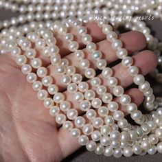 a hand holding a strand of white pearls