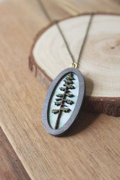 Welcome to our enchanting collection of wooden laser engraved diorama necklaces! Embrace your inner witchy vibes with these magical pieces featuring intricate designs of mushrooms, ferns, trees, and mini magic scenes. Each lightweight necklace is hand painted with care and comes on a beautiful brass chain. - Hand painted wood pieces add a unique touch to each necklace - Mini landscape scenes create a whimsical feel - Brass or gold chain adds a touch of elegance - Water resistant for everyday wea Spiritual Pendant Jewelry With Pressed Flowers, Nature-inspired Silver Brass Necklaces, Nickel-free Nature-inspired Jewelry With Round Pendant, Nature-inspired Oval Pendant Necklace For Gifts, Nature-inspired Nickel-free Jewelry With Round Pendant, Nature-inspired Silver Brass Necklace, Unique Engraved Necklace Gift, Unique Engraved Necklace As A Gift, Unique Engraved Necklace For Gift