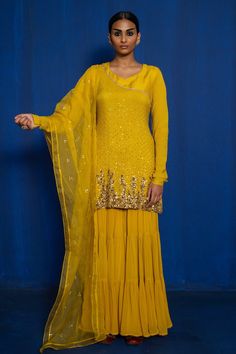 Yellow short kurta with hand embroidery of zardozi with dull gold, copper and antique sequins. Comes with tiered sharara and mukaish work dupatta.
Component: 3
Pattern: Hand Embroidered
Type Of Work: Zardozi, Mukaish, Sequins
Neckline: V-Neck
Sleeve Type: Churidar Sleeves
Fabric: Kurta: Chinon, Georgette, Dupatta: Organza, Lining: Taffeta
Color: Yellow
Other Details: 
Tiered sharara
Leaf shaped neckline
Closure: Kurta: Back zipper
Occasion: Mehendi and Haldi - Aza Fashions Fitted Sharara With Resham Embroidery For Transitional Season, Semi-stitched Sharara For Designer Wear Diwali, Bollywood Style Chinon Sharara With Zari Work, Bollywood Chinon Sharara With Resham Embroidery, Semi-stitched Chinon Sharara With Zari Work, Festive Sharara With Zari Work In Georgette, Semi-stitched Sharara With Resham Embroidery In Chinon, Festive Georgette Sharara With Zari Work, Semi-stitched Chinon Sharara With Resham Embroidery