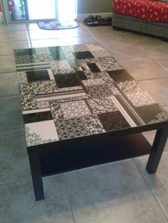 a black and white coffee table sitting on top of a tiled floor next to a bed