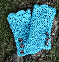 a pair of blue crocheted mittens sitting on top of a grass covered field