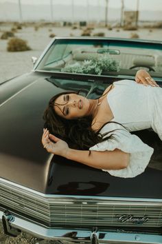 a woman laying on the hood of a car