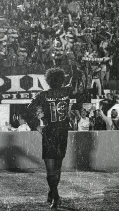 an old black and white photo of a football player holding his arms in the air