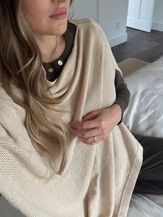 a woman sitting on top of a bed wrapped in a blanket and looking off to the side