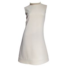 A fabulous off white wool dress by Pierre Cardin. It is an A line sleeveless dress with a stand up collar and hem highlighted with rows of top stitching around their circumferences. It is lined in off white and has a center back hand sewn metal zipper. Fits sizes Small, Medium. Marked US size 6. Bust 36" Waist 30" Hips 39" Length 38" Classic White Sleeveless Dress, Classic Wool A-line Dress, Classic White A-line Sleeveless Dress, Chic Sleeveless Wool Dress, Formal Cream Sleeveless Mini Dress, Cream Sleeveless Mini Dress For Formal Occasions, Off White Sleeveless Formal Mini Dress, Off White Sleeveless Mini Dress For Formal Occasions, Chic Cream High Neck Dress