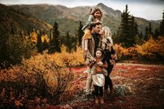 a woman and two children are posing for a photo in the woods with mountains behind them