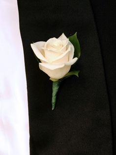 a white rose is placed on the lapel of a black suit