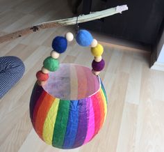 a multicolored ball hanging from the ceiling in a room with wood floors and wooden flooring