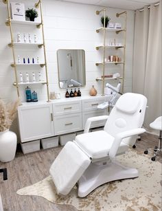 a white chair sitting in front of a mirror next to a shelf filled with bottles