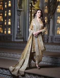 a woman standing on some steps in front of a building wearing a gold and white outfit