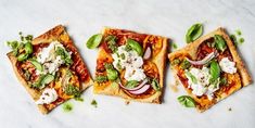 three flatbread pizzas topped with vegetables and feta cheese on a marble surface