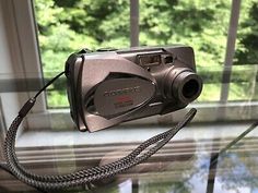 a digital camera sitting on top of a glass table next to a window sill