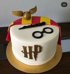 a harry potter themed cake with gold trimmings and glasses on top, sitting on a wooden table