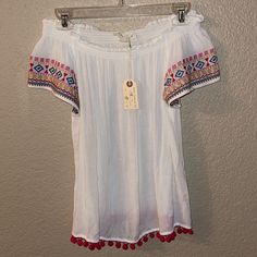 Nwt Stretchy And Off Of The Shoulder Embroidery Sleeve Detail With Tassels On The Waist Size Medium Such A Cute Top! Short Sleeve Cotton Blouse With Tassels, Cotton Short Sleeve Blouse With Tassels, Cotton Blouse With Tassels And Short Sleeves, White Embroidered Hem Blouse For Vacation, White Embroidered Blouse For Vacation, Vacation Tops With Geometric Embroidery And Short Sleeves, Geometric Embroidered Short Sleeve Tops For Vacation, Short Sleeve Tops With Geometric Embroidery For Vacation, White Top With Geometric Embroidery For Vacation