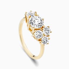 three stone engagement ring in yellow gold with diamonds on the sides and an oval diamond center