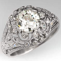 an antique style diamond ring with filigrees and diamonds on the sides, set in white gold