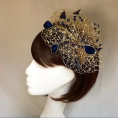 Delicate gold and navy fascinator perfect for the guest who wants something fairly understated. This design is a beautiful selection of glass effect leaves and flowers clustered together amongst a fine layer of veiling and set onto a gold ribbon base tiara band.As with all our designs, this piece can be made in any colour combination and set onto either a band or a comb which you can state either before or after orderingAs a online shop item this item can be made exact to the sample in the pictu Gold Headpiece With Round Crown For Party, Gold Round Crown Headpiece For Party, Gold Headband Fascinator For Party, Gold Headpieces For Royal Ascot Formal Occasion, Gold Costume Hats With Structured Crown For Evening, Gold Crown Costume Headpiece For Weddings, Gold Round Crown Headpiece For Weddings, Gold Wedding Headpiece With Round Crown, Gold Evening Fascinator With Pinched Crown