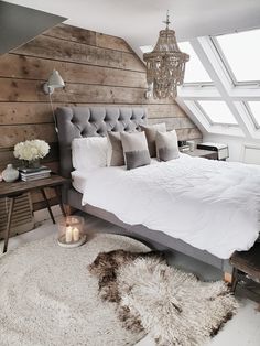 a large bed sitting under a window next to a white rug and wooden headboard