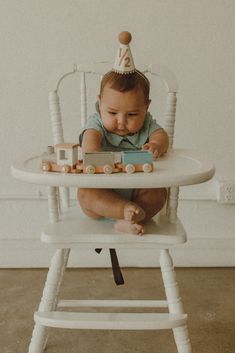 a baby sitting in a high chair with a toy train on it's seat