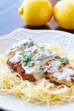 a white plate topped with chicken parmesan covered in sauce next to lemons