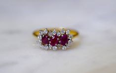 Metal: 18kt Yellow Gold Stone: Diamond And Ruby Stone Shape: Round And Oval Approximate Diamond Total Weight: .32 ctw Approximate Ruby Weight: .61 ctw Ring Size: 7 Sizable: Yes. Please state size in size/personalization box. Weight of entire piece with stones: 3.30 grams Measurements of Top Part Of Ring: 14mm Long and 8.31mm Wide Height Of Ring: 24.29 mm Shoulder Width: 1.33 mm Luxury Ruby Cluster Ring With Diamonds, Luxury Cluster Ruby Ring With Diamonds, Diamond White Multi-stone Ring For Formal Occasions, Ruby Ring With Diamond Cluster And Brilliant Cut, Cluster Ruby Ring With Brilliant Cut Diamonds, Exquisite Diamond Multi-stone Cluster Ring, Exquisite Diamond Cluster Ring With Multi-stone, Exquisite Multi-stone Diamond Cluster Ring, Luxury Cluster Ruby Ring For Anniversary