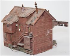 an old red wooden house with stairs and railings on the roof, in front of a white background