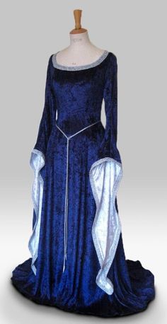 "ISOLDE IS A STUNNINGLY ELEGANT DRESS PICTURED IN NAVY BLUE AND SILVER, ALSO PICTURED IN SILVER AND ROYAL BLUE, BOTTLE GREEN AND IVORY AND PURPLE AND WHITE. DESIGNED AND CUSTOM MADE BY frockfollies AND WOULD BE PERFECT FOR SO MANY OCCASIONS: GOTHIC EVENTS MEDIEVAL/RENAISSANCE/ELVISH WEDDINGS LARP EVENTS RE ENACTMENTS HANDFASTING CEREMONIES LARP EVENTS MASQUERADE  BALLS YOUR INNER GODDESS MOMENTS! HAND MADE IN ENGLAND BY AN EXPERIENCED THEATRICAL COSTUMIER THIS OUTFIT IS AVAILABLE TO ORDER IN A WIDE RANGE OF COLORS. MADE FROM A LUXURIOUS SOFT DRAPEY  NAVY BLUE CRUSHED VELVET, THIS DRESS IS FLUID IN IT'S SIMPLICITY.  THE CLASSIC MEDIEVAL  SLEEVES WHICH ARE  LINED IN SILVER ARE TRIMMED WITH SILVER BRAID AS IS THE FLATTERING CURVED NECKLINE. A SILKY SASH CORD BELT FINISHED WITH SILVER  FILLIGR Elvish Dress, Handfasting Dress, Moda Medieval, Gothic Gowns, Medieval Wedding Dress, Medieval Gown, Medieval Gothic, Medieval Wedding, Royal Dresses