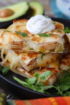 a stack of quesadillas topped with sour cream and garnished with cilantro