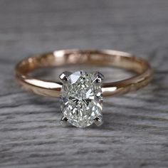 an oval cut diamond ring on top of a wooden table