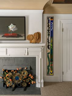 a fireplace in a living room next to a painting and vases on the mantle