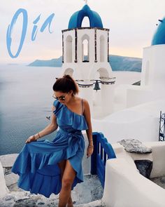 a woman in a blue dress leaning against a white building