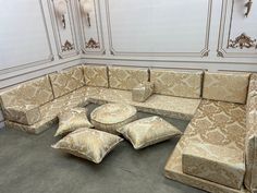 a corner couch with pillows on the floor