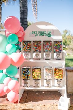 a gummy machine is set up with balloons and streamers on the front wall