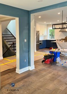 an empty room with hard wood flooring and blue paint on the walls, stairs in the background