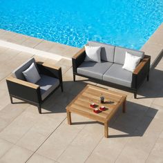 an outdoor seating area next to a swimming pool with two chairs and a coffee table