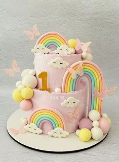 a pink cake with rainbows and clouds on it