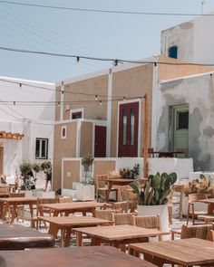 an outdoor dining area with wooden tables, chairs and potted plants on the table