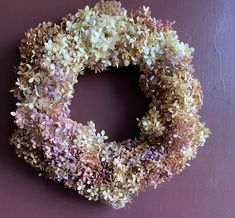 a wreath made out of dried flowers on a purple wall