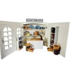 a dollhouse kitchen with open doors and shelves