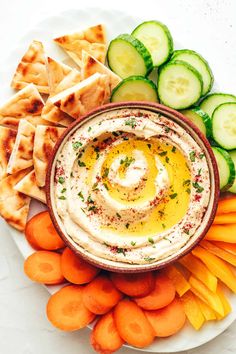 hummus, carrots, cucumbers and crackers on a plate