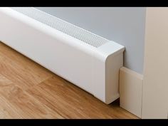 a white radiator sitting on top of a wooden floor next to a wall