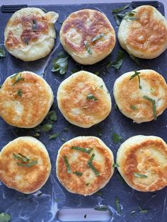 several small breads with herbs on top of them sitting on a blue tray, ready to be cooked