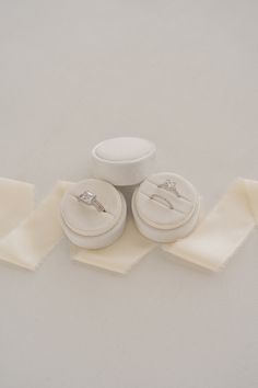 two wedding rings sitting on top of each other next to some white cloth and buttons