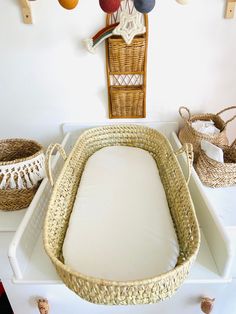 a wicker baby crib with white sheets and pillows on the floor next to wall decorations