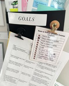 a binder with some paper on top of it next to a clipboard that says goals