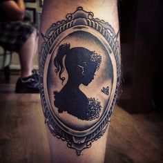 a woman's silhouette in a frame tattoo on the leg