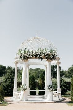 a white gazebo decorated with flowers and greenery